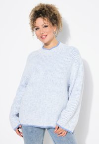 Maglione lavorato a maglia azzurro chiaro con bordi blu a contrasto, caratterizzato da una trama a costine e spalle scese, abbinato a jeans in denim chiaro.