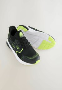 Black athletic shoes with neon green accents, mesh upper, cushioned sole, and textured design. Features a padded collar and laces.