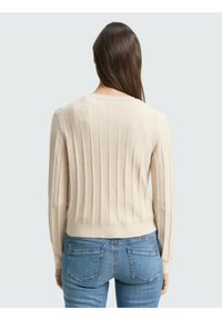 Pulover bej cu model rib, cu mâneci lungi și guler rotund, realizat dintr-un material moale. Poziționat pe un fundal deschis.