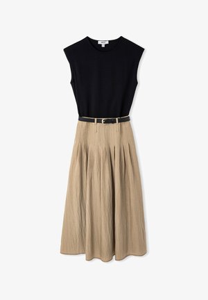 Top negro sin mangas combinado con una falda midi beige con plisados y un cinturón negro delgado con hebilla dorada.