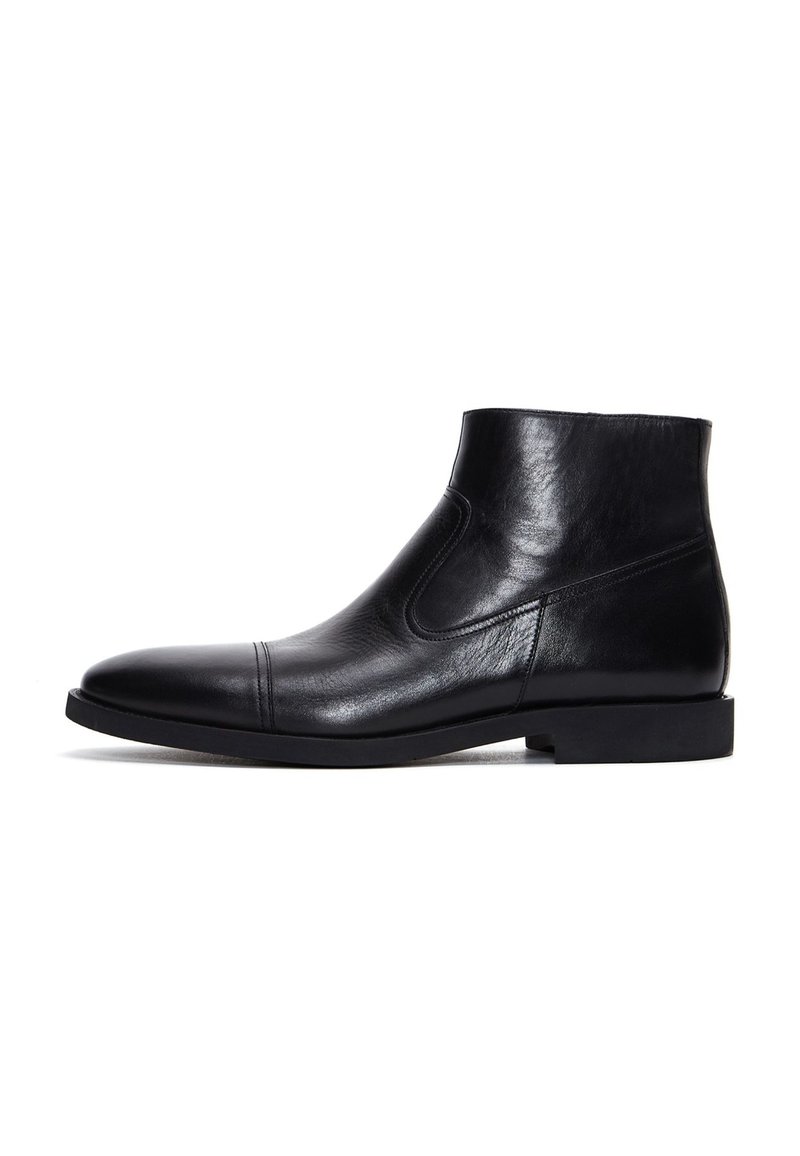 Botas de tobillo de cuero negro con una textura suave, punta redondeada, paneles laterales elásticos y una suela plana de goma.