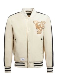 Beige bomberjakke med sorte sidedele, trykknaplukning, ribbede stribede manchetter og et tigeremblem på brystet med teksten "EST. 2001."