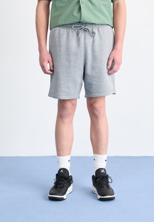 Gray sweat shorts with an elastic waistband and drawstring detail, paired with black athletic shoes and white Nike logo socks.