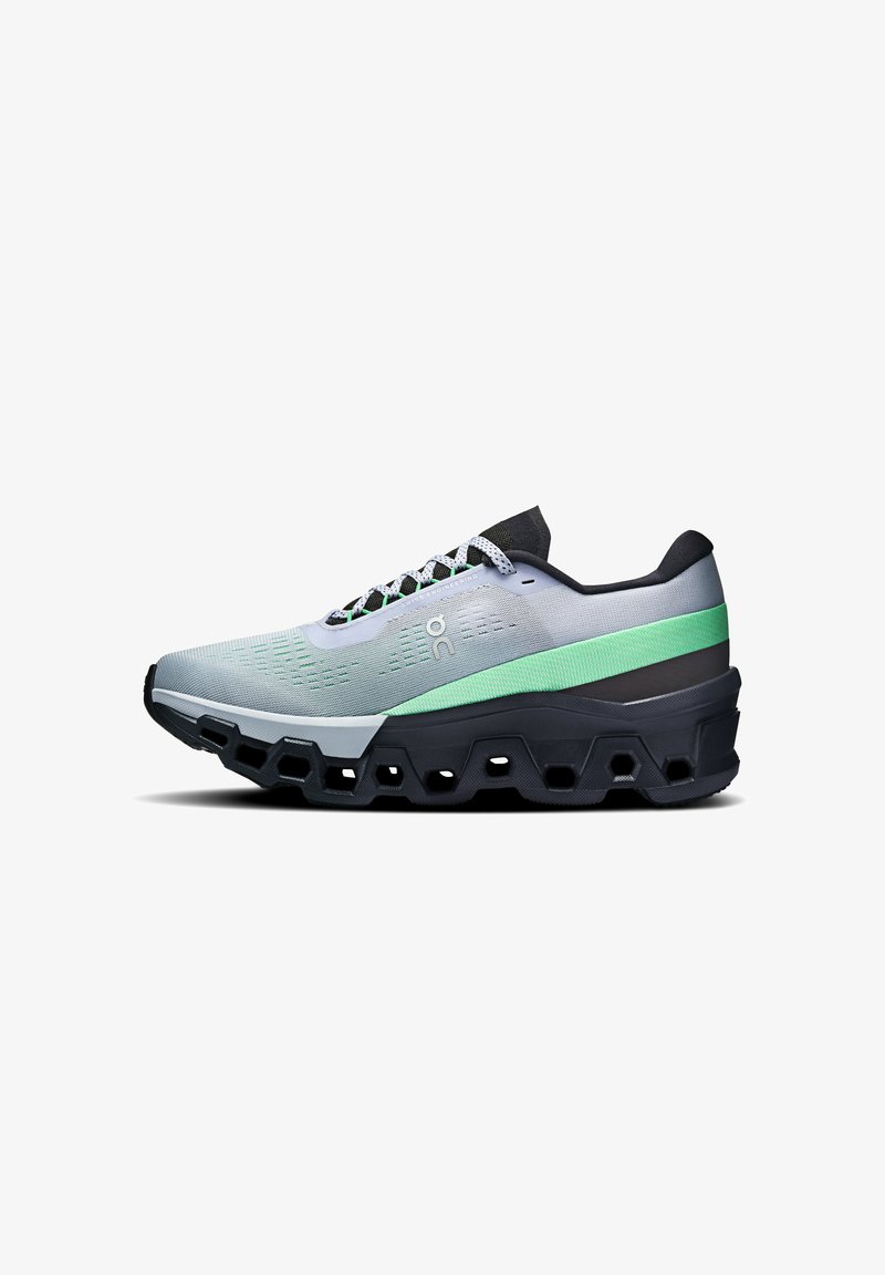 Running shoe in grey with green and black accents. Features a textured mesh upper and thick, segmented sole for cushioning and support.