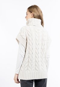 Kabelstrick-Wollweste in Creme, mit hohem Kragen und kurzen Ärmeln. Texturiertes Muster mit geripptem Saum und offenen Maschen-Details.