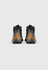 Bottes de randonnée avec une tige synthétique noire et des accents bruns, design montantd, panneaux en mesh texturé et semelles en caoutchouc robustes pour la traction.