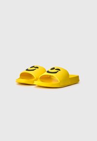 Yellow slide sandals made of soft plastic with an open-toe design. Features a black smiling face graphic on each strap.