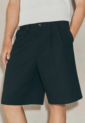 Black tailored shorts made of smooth material, featuring a pleated front, side pockets, and a button closure at the waist.