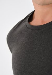 Donkergrijze t-shirt met een ronde hals, gemaakt van zachte, gestructureerde stof, met een getailleerde vorm die de contouren van het bovenlichaam benadrukt.