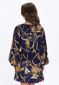 Tengerészkék ruha aranylánccal és virágmintákkal, hosszú ujjakkal, derékrésznél megkötve, kulcslyuk részlettel a háton.