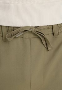 Olívazöld elasztikus derekú nadrág, texturált felülettel, megkötővel a derekán és oldalzsebekkel a funkciókészségért.