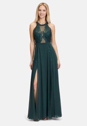 Robe de soirée teal avec un corsage en dentelle transparente, un col haut et une jupe ouverte avec une fente latérale. Le tissu fluide et doux crée un look élégant.