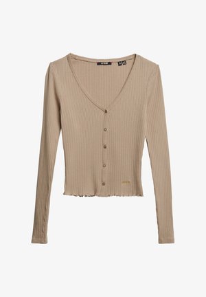 Beżowy kardigan z długim rękawem w prążki, z dekoltem w kształcie litery V, z zapięciem na guziki z przodu i skróconym dołem. Posiada delikatne szycie i mały akcent z logo.