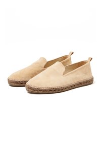Des chaussures slip-on en daim beige avec un embout arrondi, une doublure en toile et une semelle en corde de jute, dotées d'une petite languette à l'arrière pour un enfilage facile.