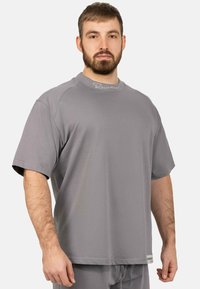 Camicia grigia a maniche corte in tessuto morbido, con collo a giro e dettagli del logo minimalisti sul collo.
