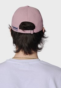 Rosa bomull baseballkeps med justerbar rem bak, med blå broderi "hummel SPORTSWEAR" på sidan.