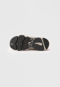 Talpa din cauciuc negru cu profil texturat, talpa intermediară de culoare neutră și deschideri de ventilație, având un design aerodinamic și athletic.