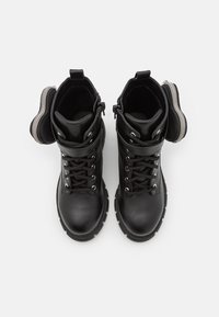 Zwarte leren enkelboots met vetersluiting aan de voorkant, gevoerde schacht en een ritssluiting aan de zijkant voor accessoires. Dikke rubberen zool voor grip.