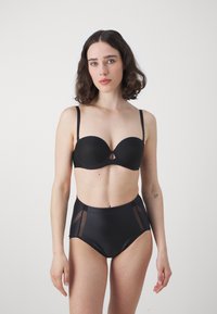 Zwart lingeriesetje met een gepadded strapless bh met een sleutelgatopening en hoogoplopende slipjes met doorzichtige paneelaccenten. Gelijkmatige textuur.