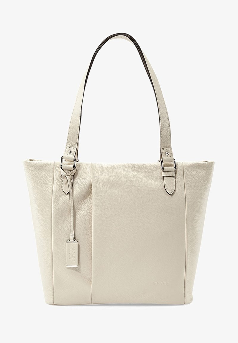 Sac fourre-tout en cuir beige avec deux sangles d'épaule réglables, coutures minimales et une petite étiquette rectangulaire suspendue à une sangle.