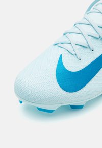Light blue soccer cleat with textured upper, featuring a large blue Nike swoosh and light blue studs for traction. Lace-up design.