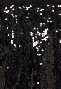 Schwarzer Stoff, der mit unterschiedlich großen, glänzenden, silbernen Pailletten bedeckt ist und eine strukturierte Oberfläche mit reflektierenden Eigenschaften erzeugt.