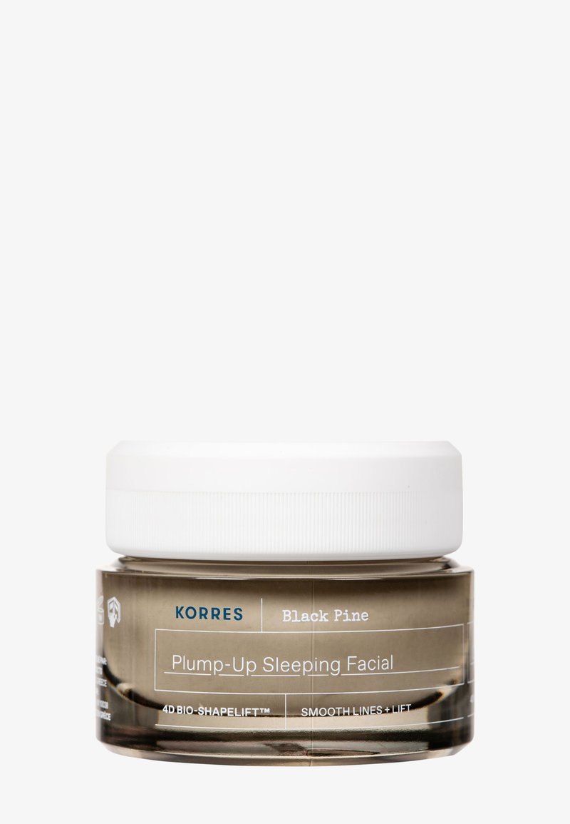Korres Black Pine Plump-Up Sleeping Facial w przezroczystym słoiku z białą pokrywką; posiada okrągły kształt i nadrukowane etykiety na pojemniku.