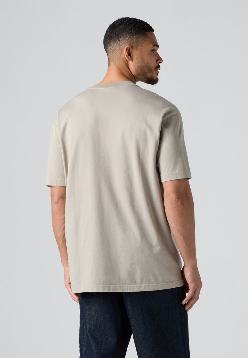 Beige Baumwoll-T-Shirt mit kurzen Ärmeln, rundem Halsausschnitt und lockerer Passform. Weiche Textur und leicht verlängertes Rückenteil.
