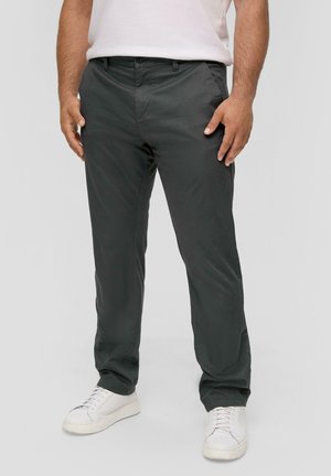 Dunkelgraue Chinos mit schlanker Passform, aus leichtem Stoff gefertigt, mit seitlichen Taschen und einem Knopfverschluss; kombiniert mit weißen Sneakern.