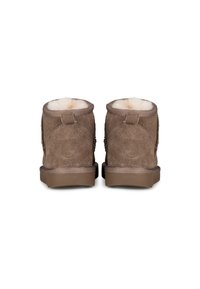 Bruine suède enkellaarsjes met faux fur voering, platte zool en een kleine hak. Voorzien van een achterste trekhaak en decoratieve stiksels langs de zijkanten.