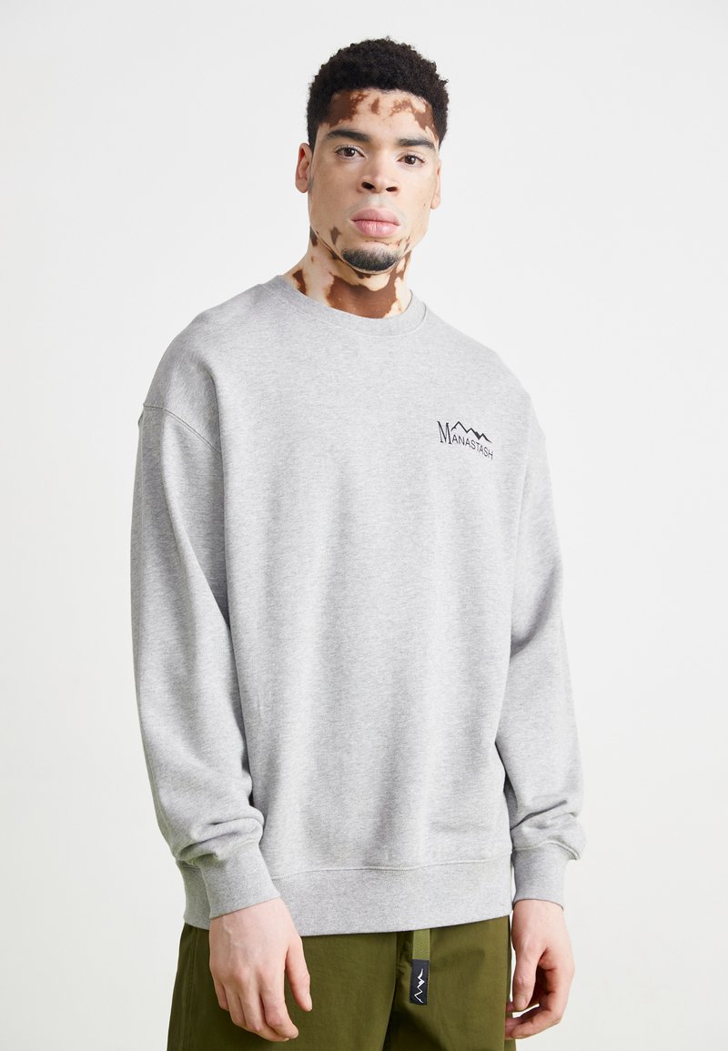 Gray sweatshirt with a crew neck and long sleeves, featuring a black mountain logo on the chest. Soft texture, casual fit.