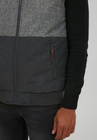 Grau und schwarze Zip-Jacke aus strukturiertem Stoff, im Farbblockdesign, mit gerippten Bündchen und einer seitlichen Reißverschlusstasche mit Lederakzent.