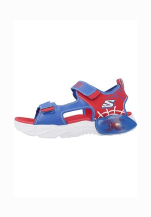 Kindersandaal met open teen in blauw en rood met verstelbare riempjes, witte zool, spinnenafbeelding en spinnenwebdesign op de hiel.