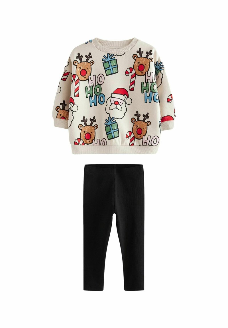 Pullover sweater med rensdyr, julemand og gaver på en cremefarvet baggrund, parret med sorte ribbede leggings.