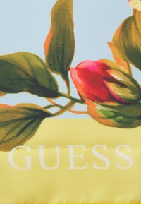 Sciarpetta in raso con un design floreale caratterizzato da un fiore rosa e foglie verdi su uno sfondo azzurro chiaro. Accentuata da dettagli gialli e testo "GUESS".