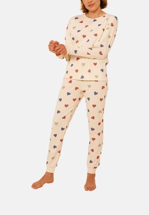 Crème katoenen loungewear set met lange mouwen en broek, versierd met meerkleurige hartpatronen in rood, blauw en groen. Zachte stoftextuur.
