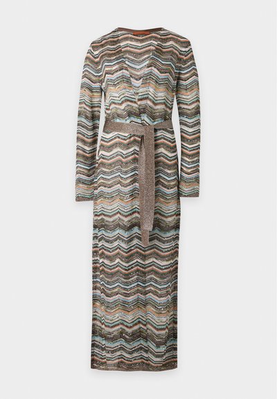 Robe portefeuille à manches longues avec un motif zigzag multicolore et une ceinture métallique nouée à la taille sur un fond uni.