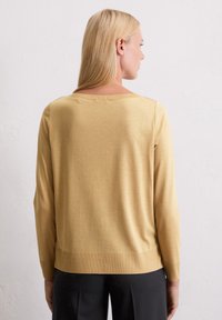 Hellgelbes, langärmliges Sweatshirt mit lockerer Passform, weichem Textil und geripptem Saum. Ansicht von hinten, die den Halsausschnitt und das Ärmel-Design zeigt.
