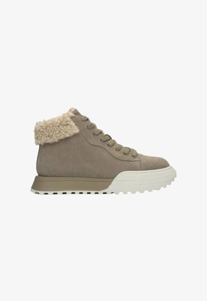 Beige Wildleder-Stiefelette mit einem flauschigen beigen Kragen, olivgrünen Ösen und einer klobigen weißen Gummisohle mit strukturiertem Profil.