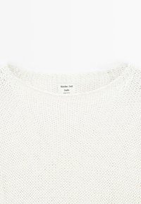 Biała sweter dziany z okrągłym dekoltem i otwartą fakturą. Metka widoczna na środku, wskazująca markę i pochodzenie.