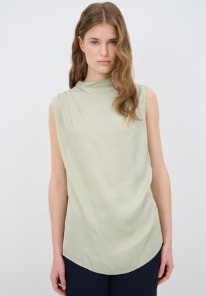Blusa senza maniche verde chiaro con una morbida caduta, caratterizzata da un colletto alto e un orlo arrotondato. Il tessuto ha una consistenza liscia e leggermente lucida.
