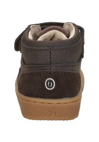 Bruine suede en leren kinderlaars met een klittenbandsluiting, ronde vorm en rubberen zool. Voorzien van een circulair logo op de hiel. Maat 21.