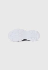 Semelle de sneaker Lacoste, en caoutchouc blanc prédominant, présentant un motif de grip texturé, des rainures circulaires et en zigzag, ainsi qu'une subtile inscription de marque.