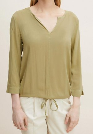 Olijfgroene, lichte blouse met een V-hals, driekwartmouwen en een trekkoord in de taille. Zachte textuur, minimale stikdetails.