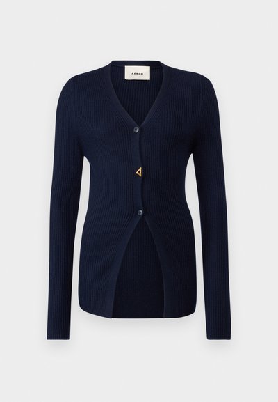 Cardigan a coste blu navy con scollo a V, maniche lunghe, chiusura con un bottone singolo e un'accento triangolare dorato vicino all'apertura.