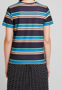 Top de manga corta con rayas horizontales en turquesa, amarillo, naranja y azul sobre un fondo negro, con un escote redondo.