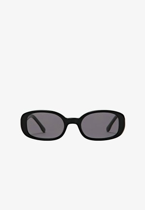 Lunettes de soleil ovales noires avec monture épaisse et verres foncés, présentées sur un fond blanc uni.