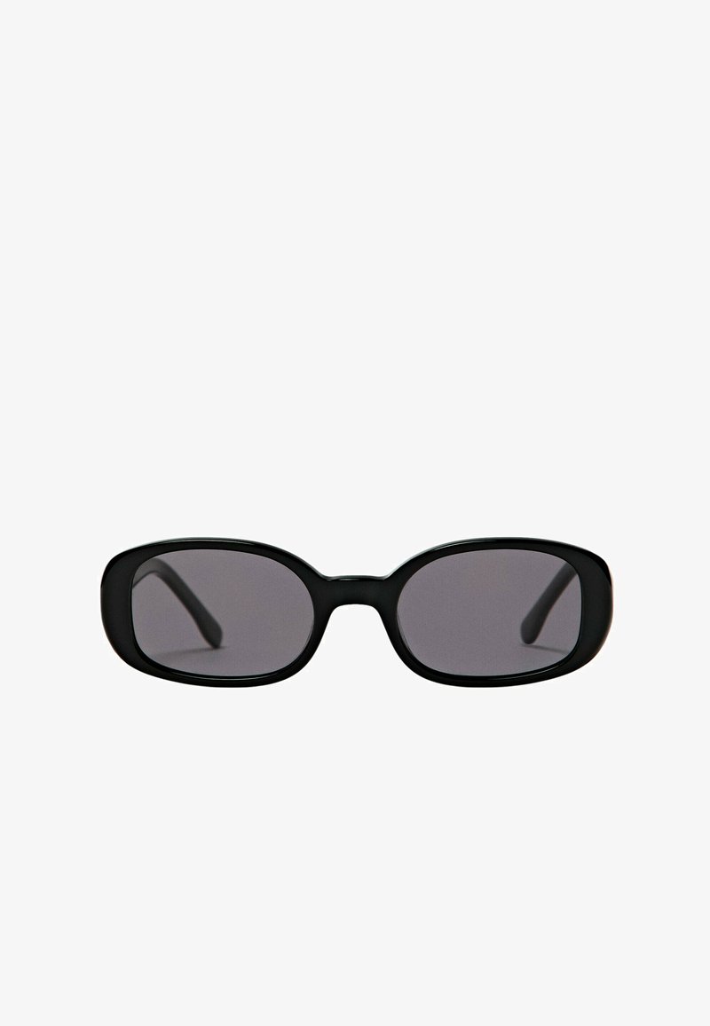 Lunettes de soleil ovales noires avec monture épaisse et verres foncés, présentées sur un fond blanc uni.