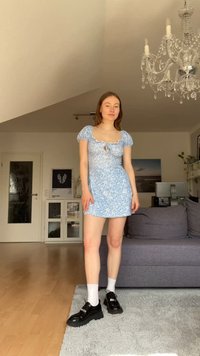 Vestido floral azul claro con mangas abullonadas y un detalle de ojal, combinado con zapatos de plataforma negros y calcetines blancos, ubicado en una habitación luminosa.