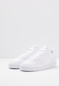 Vita sneakers med en slät syntetisk ovandel, perforerat tåparti, platta snörningar, vadderad krage och en texturerad gummisula.
